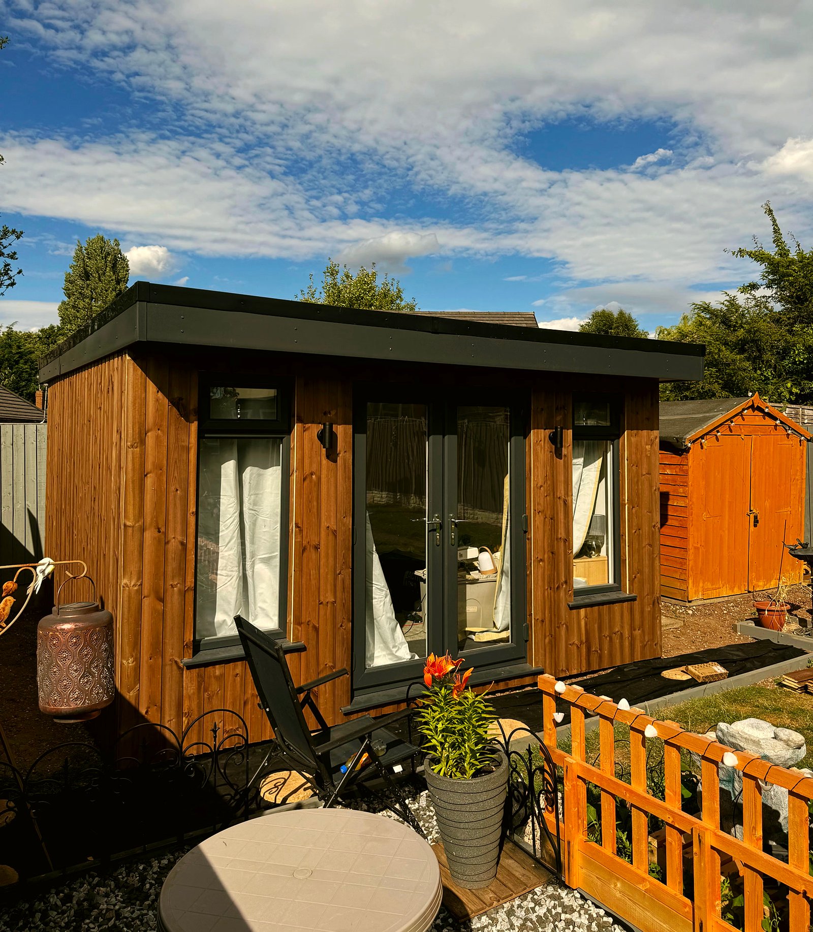 The 3m x 4m timber garden room from an angle, with garden chairs in front