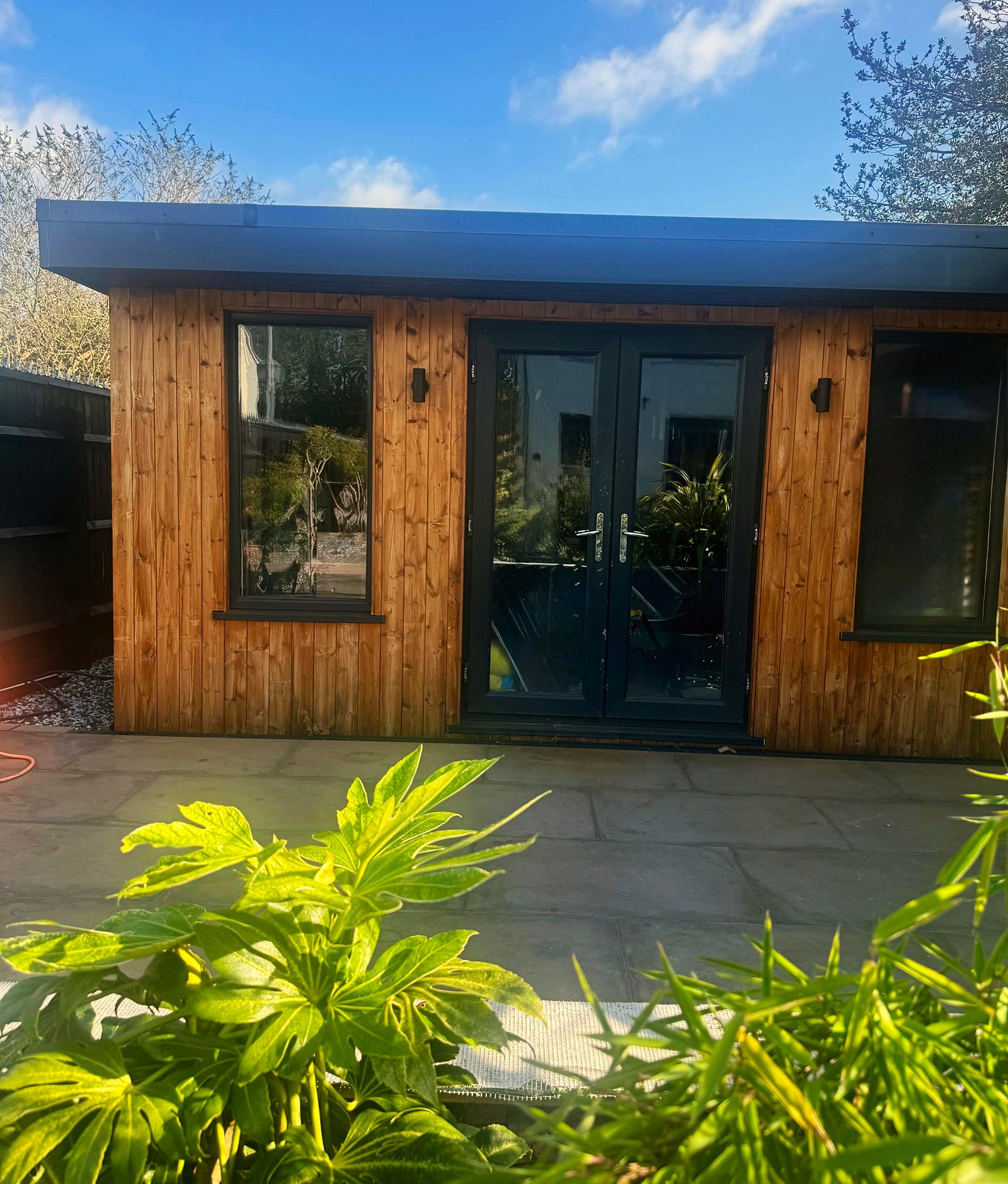 Anthracite French doors on a timber garden room, plants in front